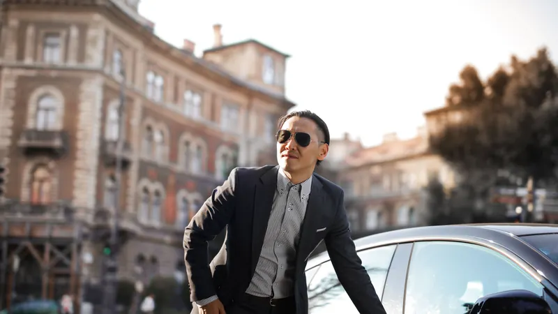 Un chauffeur en costume et lunettes de soleil près de sa voiture