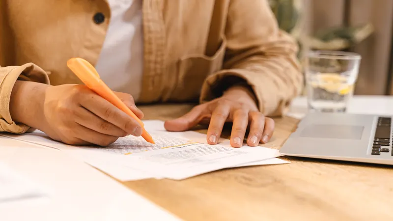 Une personne surligne ses notes de cours à côté d'un ordinateur portable